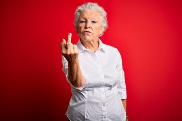 Wall Mural - Senior beautiful woman wearing elegant shirt standing over isolated red background Showing middle finger, impolite and rude fuck off expression