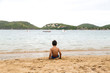© AlexPhotoStock - A lonely brazilian boy sitting on the sand on a beach of Brazil. View of his backs. Ferradura Beach, Buzios.