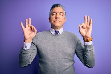 Sticker - Middle age handsome grey-haired man wearing elegant sweater over purple background relax and smiling with eyes closed doing meditation gesture with fingers. Yoga concept.