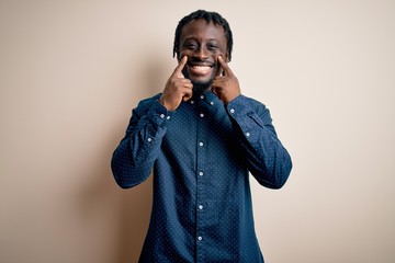 Poster - Young handsome african american man wearing casual shirt standing over white background Smiling with open mouth, fingers pointing and forcing cheerful smile