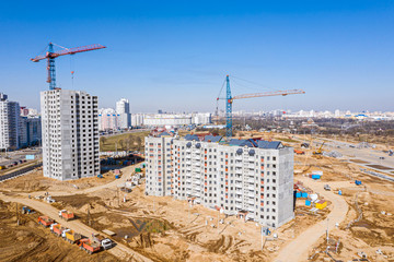 new multistory residential buildings under construction. tower cranes against blue sky background