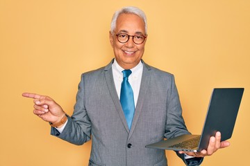 Wall Mural - Middle age senior grey-haired business man wearing glasses working using computer laptop very happy pointing with hand and finger to the side