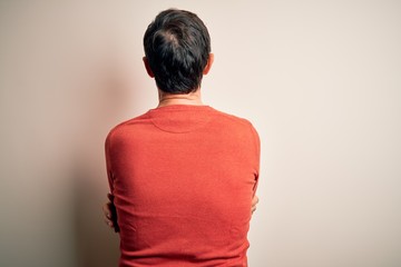 Middle age hoary man wearing casual orange sweater standing over isolated white background standing backwards looking away with crossed arms