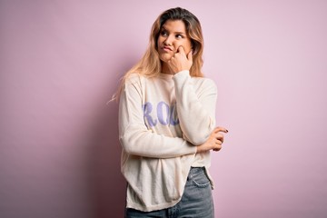 Poster - Young beautiful blonde woman wearing casual sweater standing over pink background with hand on chin thinking about question, pensive expression. Smiling with thoughtful face. Doubt concept.