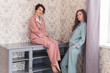 © satura_ - Two female sisters or friends relaxing at the living room. Girls in stylish pajamas. Quarantine and stay at home concept.