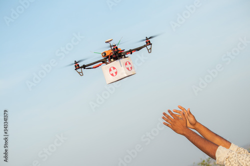 Drone Delivering First Aid Box or medicine to costumer hand during covid-19 or coronavirus lockdown - Advancing Medical Industry Logistics for Drug Transport concept.
