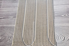 A Close Up On Electric Radiant Floor Heating System Installation Under Wood Laminate Flooring During House Renovation.