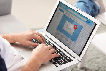 Young man with laptop checking his e-mail at home