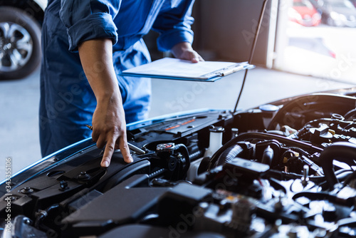 Fotomural Car mechanic holding clipboard and checking to maintenance vehicle by customer claim order in auto repair shop garage