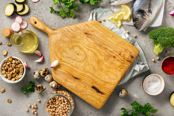 Wall Mural - Top view healthy food background. Wooden board with various wholesome food. Fresh fish, vegetables, herbs and legumes on gray background