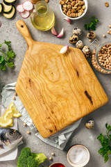 Poster - Healthy food background. Wooden board with various wholesome food. Fresh fish, vegetables, herbs and legumes on gray background top view