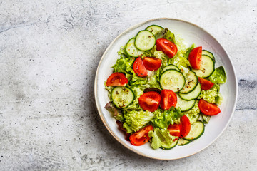 Wall Mural - Fresh tomato and cucumber salad in white bowl, gray background. Healthy food concept.