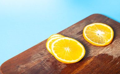 Sliced ​​orange on a wooden plate, blue background