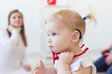 Baby girl wearing a hearing aid. Disabled child, disability and deafness concept.