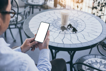 cell phone Mockup image blank white screen.man hand holding texting using mobile on desk at coffee shop.background empty space for advertise text.people contact marketing business,technology