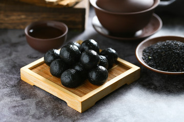 Chinese black sesame ball on bamboo plate with tea