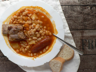 Canvas Print - Spanish Asturian fabada in a white plate, spoon on wooden table