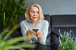 © JENOCHE - Serious woman attending a phone call sitting on a sofa in the living room at home