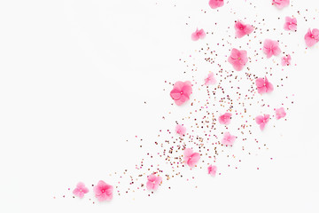 Wall Mural - Gold glitter confetti and pink flowers splash on white background. Spring Holidays frame. Birthday, Mothers Day card. Flat lay.