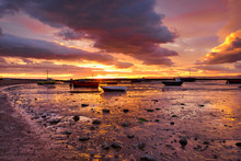 Sunset Over Beached Fishing Boats In Morecambe Bay, Lancashire, England. The Estuary Of Morecambe Bay Is The Largest Area Of Intertidal Mudflats And Sand In The United Kingdom