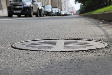 Asphalt Road, storm drain hatch blurred