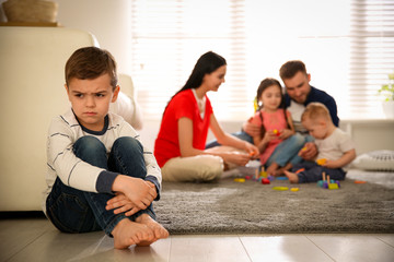 Canvas Print - Unhappy little boy feeling jealous while parents spending time with other children at home