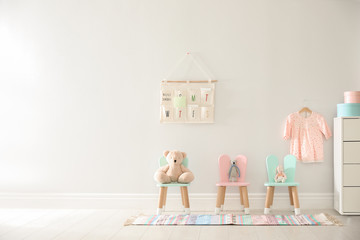 Poster - Cute toys on chairs with bunny ears near white wall indoors, space for text. Children's room interior