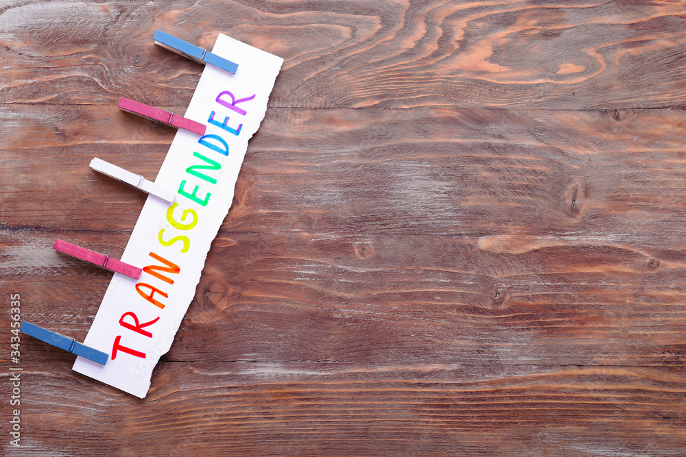 Paper sheet with word TRANSGENDER on wooden background