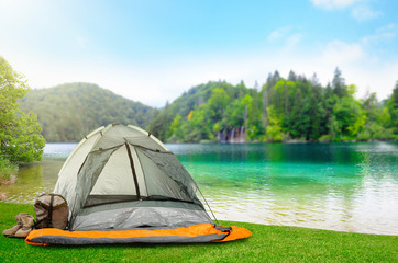camping tent with sleeping bag and boots near beautiful river