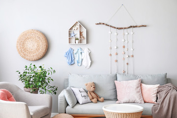 Stylish interior of children's room with sofa and clothes