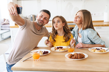 Wall Mural - Photo of funny taking selfie on smartphone while having breakfast