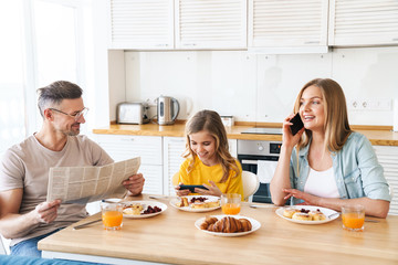 Canvas Print - Photo of family using smartphones while having breakfast