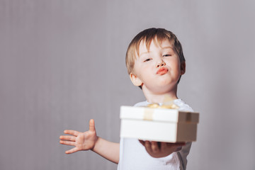 Canvas Print - Beautiful little boy in a white T-shirt holding a gift in his hand, mother's day, Valentine's day, March 8, birthday