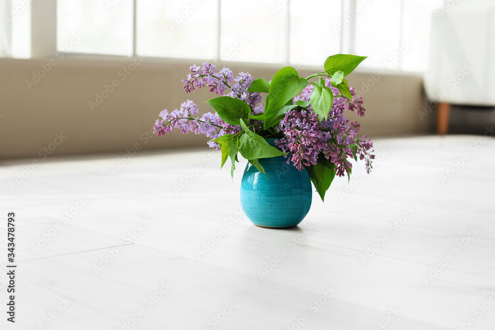 Vase with beautiful lilac flowers on floor in room