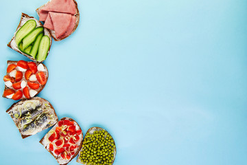 Sticker - Assorted open-faced sandwiches, sandwiches with slices of sourdough with various fillings on a blue background, top view. Flat lay. Copy space