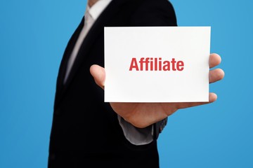 Affiliate. Business man in a suit holds card at camera. The term Affiliate is in the sign. Symbol for business, finance, statistics, analysis, economy