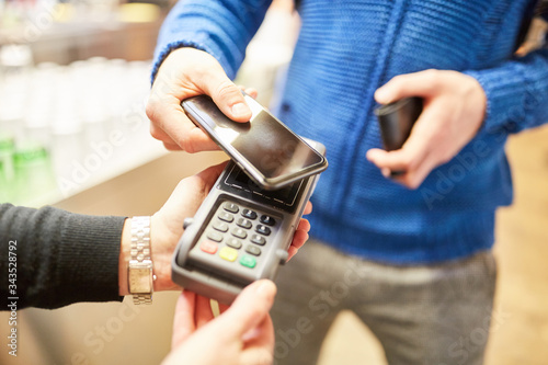 Fotomural Customer pays contactless with smartphone via NFC
