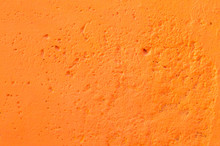 Bright Orange Rough Cement Background With The Texture Of A Concrete Wall. Non-uniform Surface With Porous Holes.