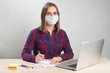 © evsafronov - Woman in a medical mask works from home at the computer during quarantine of coronavirus