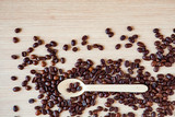 Fototapeta Tematy - coffee beans on a wooden table, with an eco-friendly wooden spoon .Light wooden background, with space for text and copying
