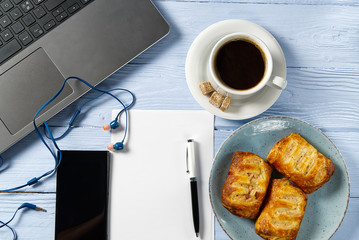 Poster - Laptop with cup of coffee and bakery on light blue old wooden table. Notebook with cup of fresh coffee in home office. Working from home concept