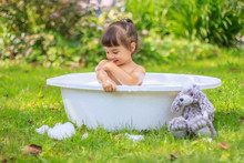 Baby Girl Bathes In A Bathtub In The Summer Garden