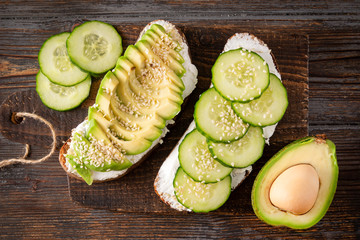 Wall Mural - sandwiches with cheese, avocado and cucumber on a dark wooden background, Breakfast, snack,