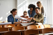 © BalanceFormCreative - Group of design students sitting in classroom and examining blueprint homework project.
