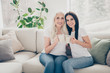 © deagreez - Portrait of two nice attractive lovely sweet cute cheerful cheery women sitting on divan drinking cacao spending free spare time morning in white light interior house flat apartment