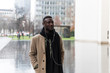 © Nektarstock - Young Black Man in Beige Coat and Earphones Walking in City