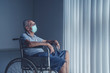 © Creativa Images - Aged man wearing face mask sitting in a wheel chair alone