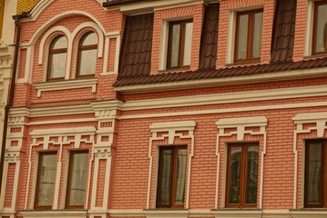 Canvas Print - texture of a series of windows on the brown red brick wall of a large multi-storey building on a city street