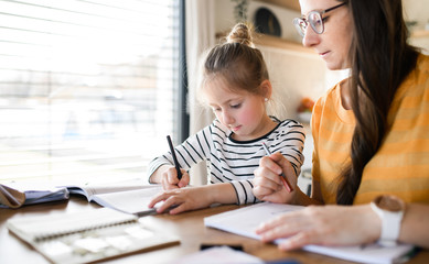 Mother and daughter learning indoors at home, Corona virus and quarantine concept.