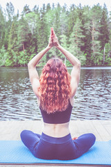 Wall Mural - Young girl practicing yoga in the nature on the lake. Female happiness. Concept of healthy life and natural balance